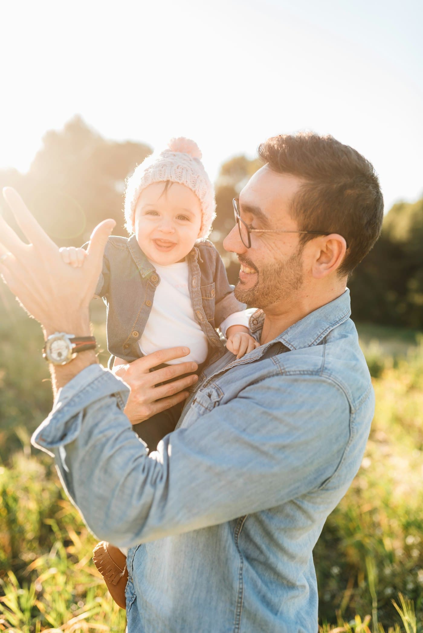 A father lifting his smiling baby in the sun